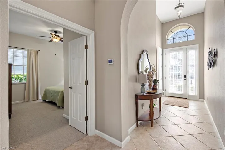 Entrance foyer featuring light tile patterned flooring, arched walkways, and light carpet