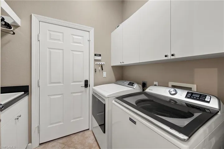 Laundry room featuring cabinet space, light tile patterned floors, and independent washer and dryer