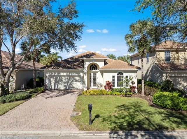 Mediterranean / spanish home featuring stucco siding, decorative driveway, a garage, a front yard, and a tiled roof