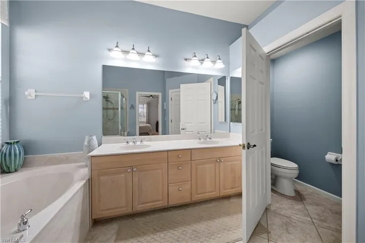 Full bath with double vanity, a garden tub, light tile patterned flooring, a shower stall, and ensuite bath