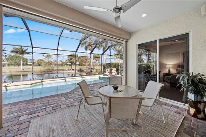 View of patio with an outdoor pool, a lanai, a water view, a ceiling fan, and a sunroom