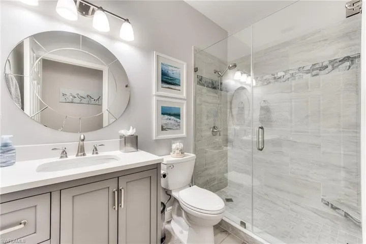 Bathroom with toilet, vanity, and a shower with door