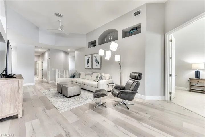 Living room with ceiling fan, a towering ceiling, and light hardwood / wood-style floors