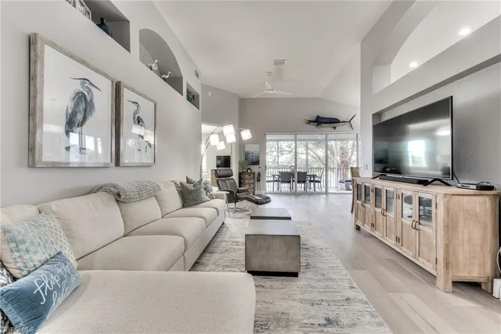Living room featuring lofted ceiling, ceiling fan, and light hardwood / wood-style floors