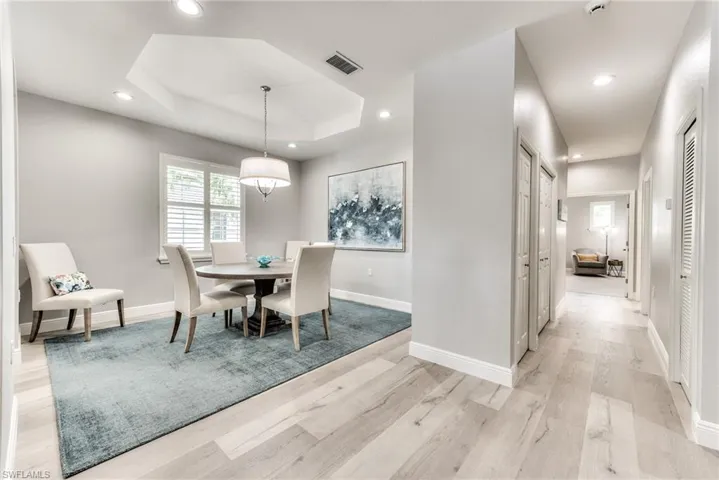 Dining area with light hardwood / wood-style floors and a raised ceiling