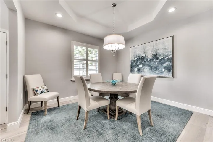 Dining space with an inviting chandelier, a tray ceiling, and light hardwood / wood-style flooring