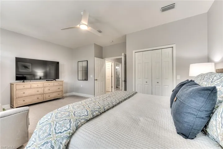 Carpeted bedroom with ceiling fan and a closet