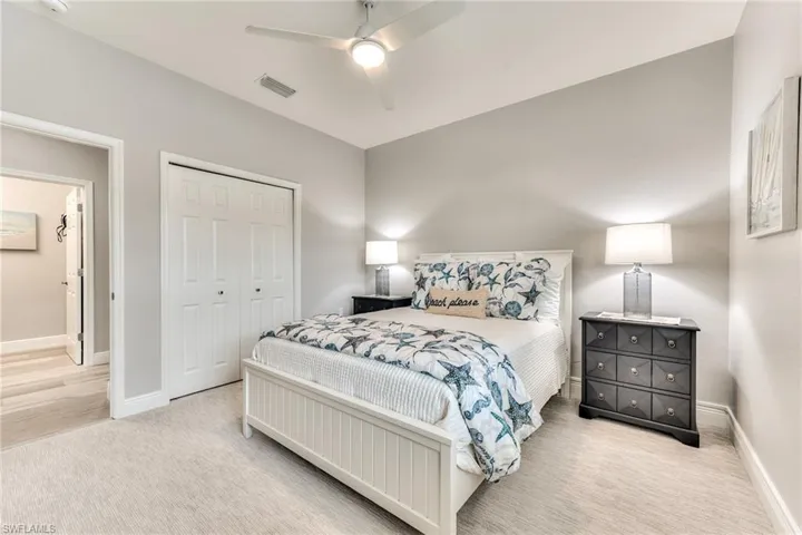 Carpeted bedroom with ceiling fan and a closet