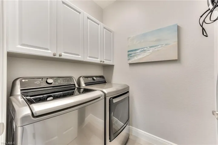 Washroom featuring cabinets and washing machine and dryer