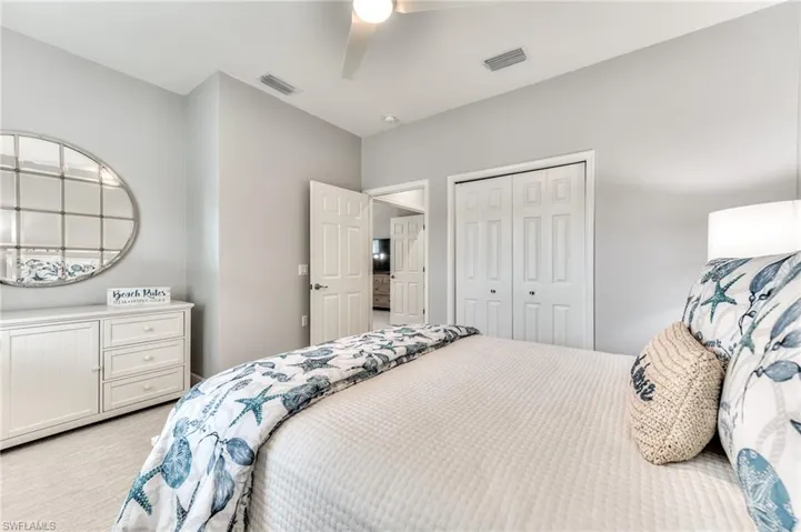 Carpeted bedroom with ceiling fan and a closet