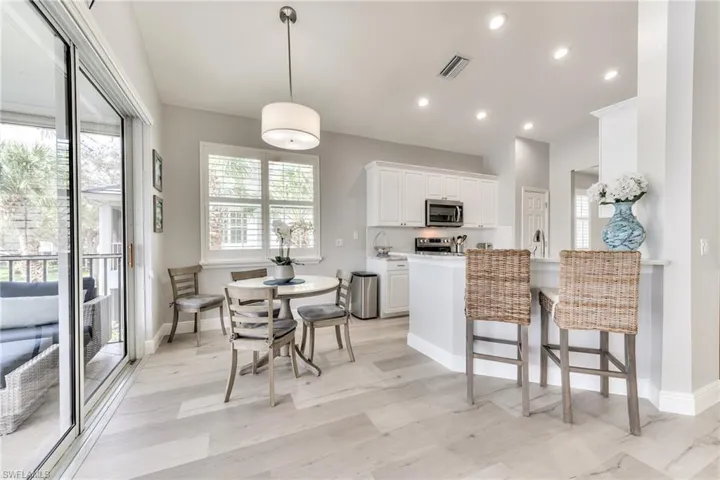 Kitchen featuring appliances with stainless steel finishes, a healthy amount of sunlight, white cabinetry, and light stone counters