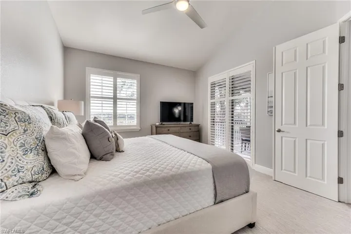 Carpeted bedroom with ceiling fan, access to exterior, and lofted ceiling