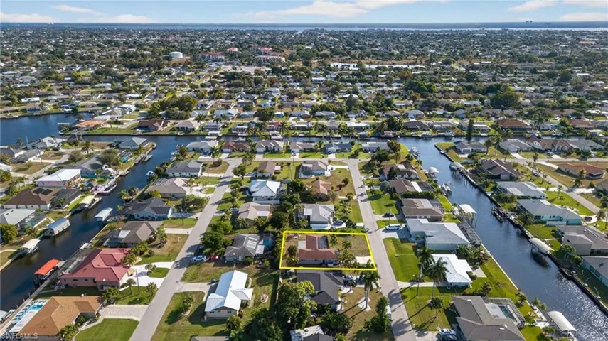 Aerial overview of property's location featuring nearby suburban area, property boundaries highlighted, and a nearby body of water