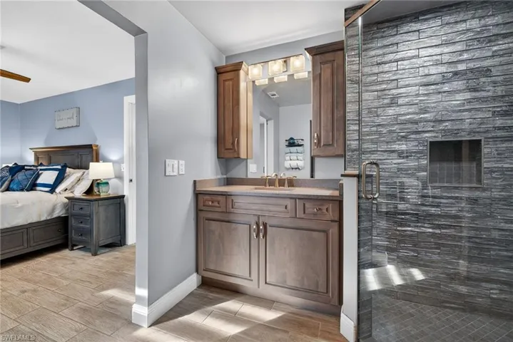 Ensuite bathroom with vanity, a shower stall, wood tiled floors, and a ceiling fan