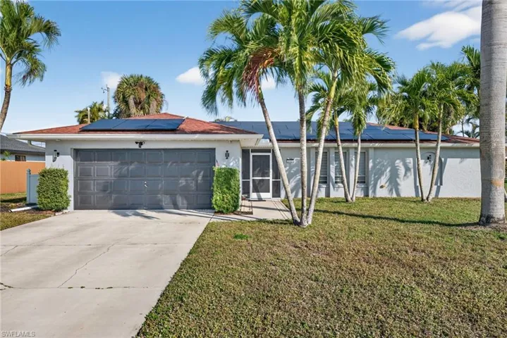 Single story home featuring stucco siding, solar panels, an attached garage, and concrete driveway