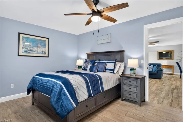 Bedroom featuring a barn door, light wood-style floors, connected bathroom, and a ceiling fan