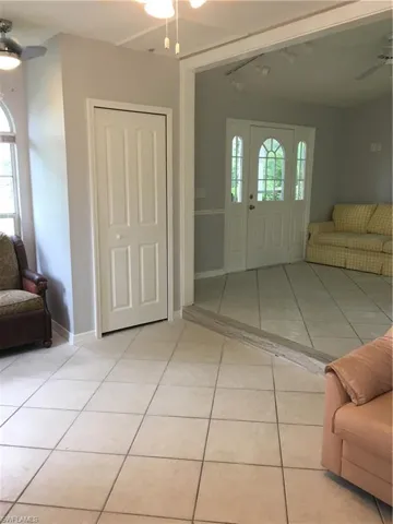 Foyer with light tile patterned flooring, rail lighting, and ceiling fan
