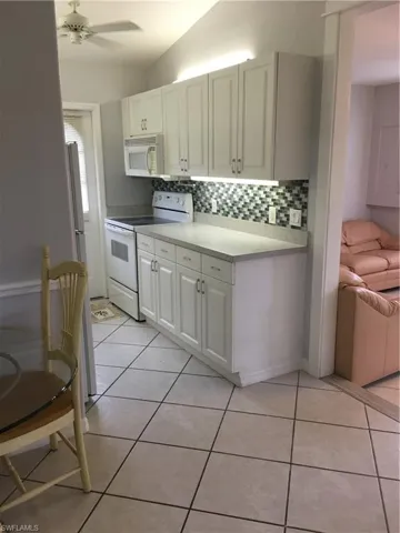 Kitchen with white cabinets, white range, ceiling fan, and light tile patterned flooring