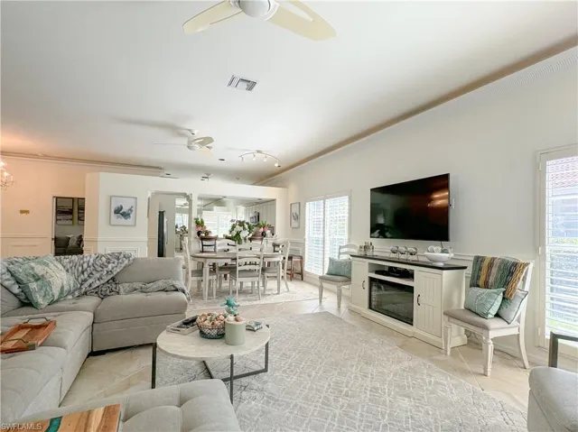 Living room with ceiling fan, crown molding, and light tile floors