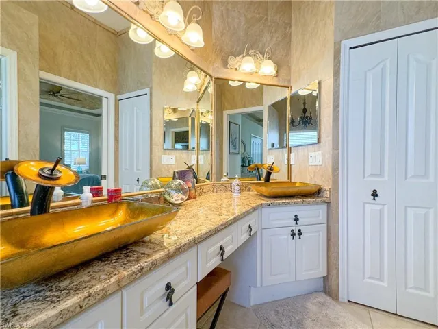 Bathroom with tile flooring, ceiling fan, oversized vanity, and dual sinks