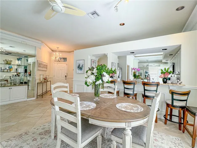 Dining space featuring crown molding, light tile floors, and ceiling fan with notable chandelier