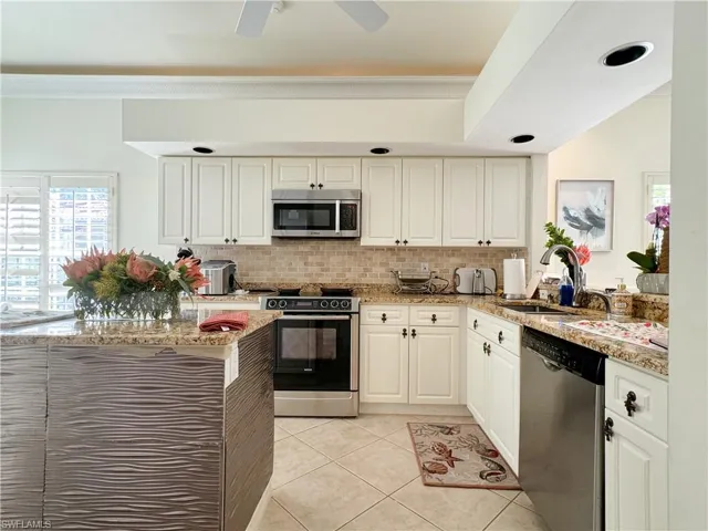 Kitchen with ceiling fan, light tile floors, sink, white cabinetry, and appliances with stainless steel finishes
