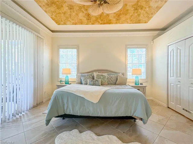 Tiled bedroom with a tray ceiling, a closet, and ceiling fan