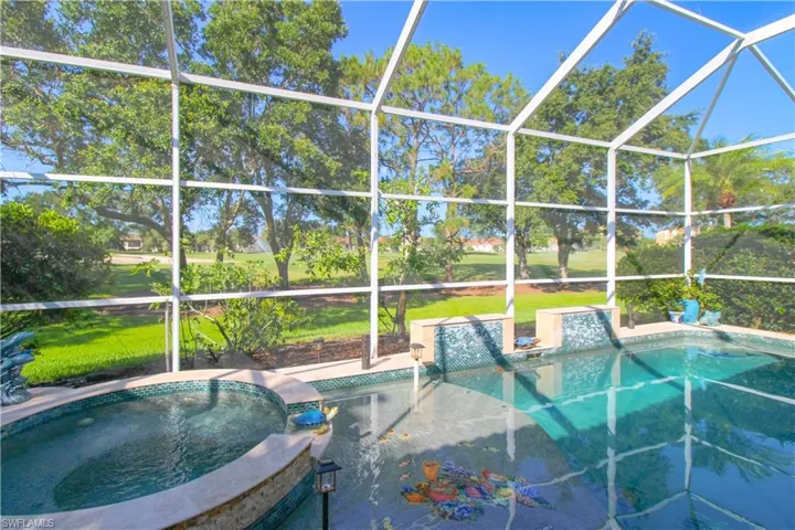 View of swimming pool featuring glass enclosure, an in ground hot tub, area for grilling, and a lawn
