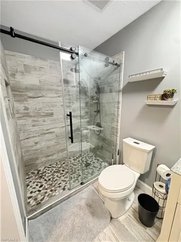 Bathroom with a textured ceiling, a stall shower, vanity, and wood finished floors