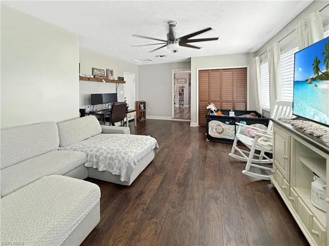 Living area featuring an office area, a textured ceiling, dark wood-type flooring, and a ceiling fan