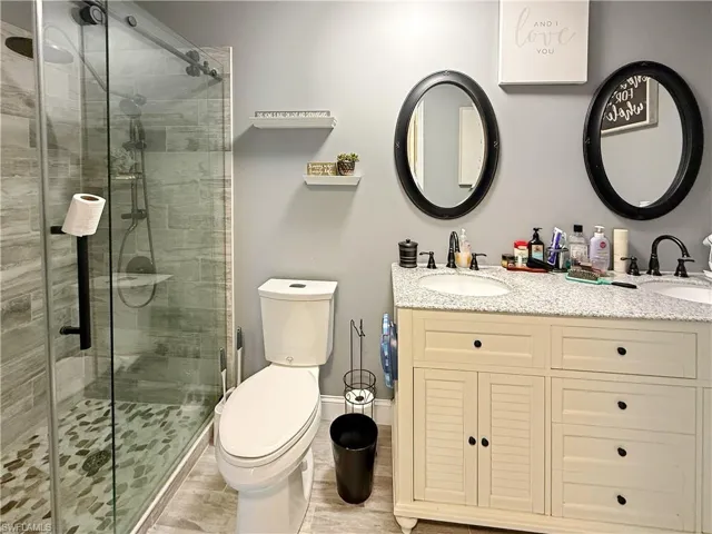 Full bathroom with double vanity and a shower stall