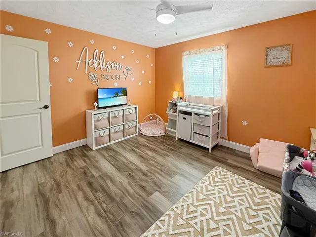 Rec room with a textured ceiling, light wood finished floors, and ceiling fan