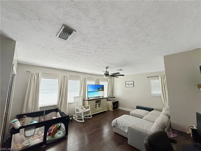 Living room featuring a textured ceiling, healthy amount of natural light, and dark wood finished floors