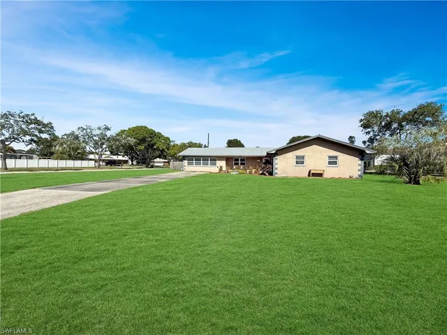 Ranch-style house with driveway, a front lawn, and stucco siding