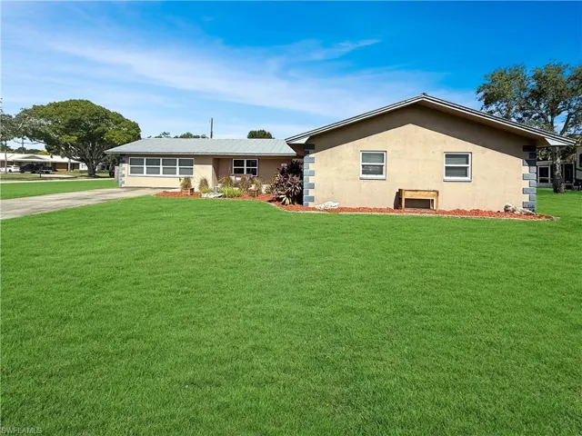 Single story home with stucco siding, a front lawn, and driveway