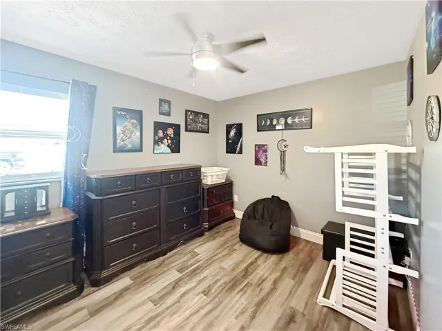 Bedroom featuring light wood-style flooring, a textured ceiling, and a ceiling fan