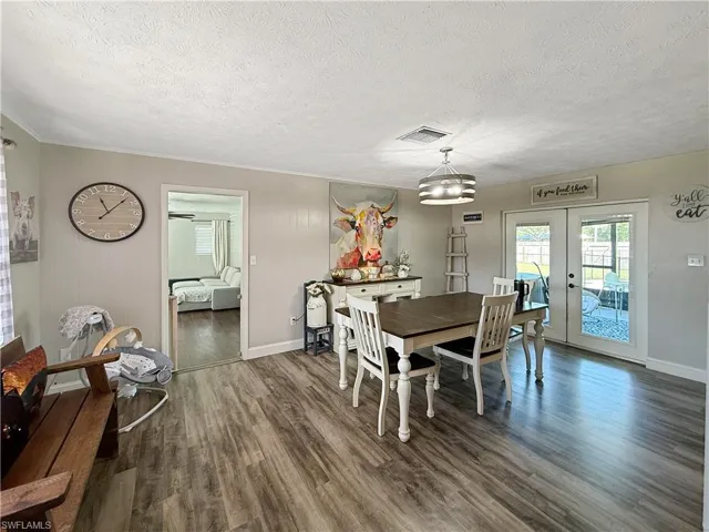 Dining space with french doors, wood finished floors, and a textured ceiling