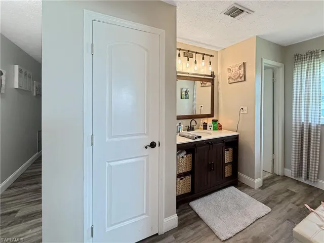 Full bath with a textured ceiling, light wood-type flooring, and vanity