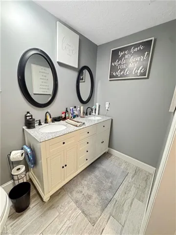 Bathroom with double vanity, a textured ceiling, and light wood finished floors