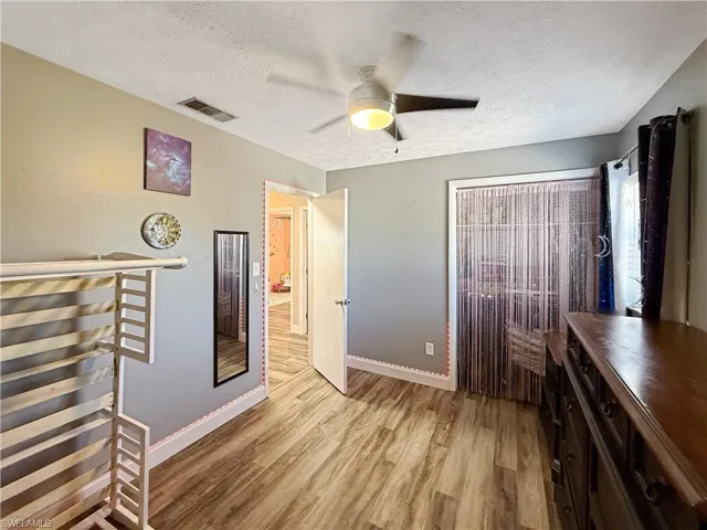 Bedroom featuring light wood-type flooring, a textured ceiling, and ceiling fan