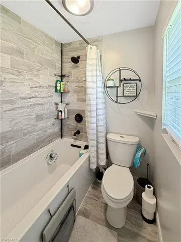 Bathroom with shower / bath combo with shower curtain, a textured ceiling, and light wood finished floors