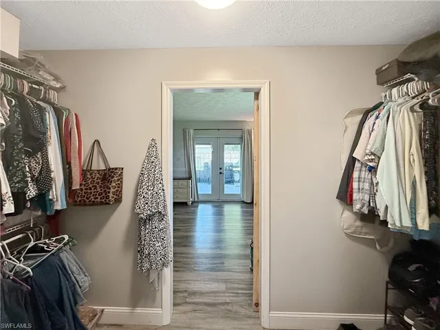 Walk in closet with light wood finished floors and french doors