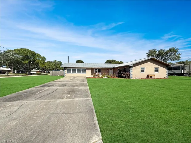 Ranch-style house featuring concrete driveway and stucco siding