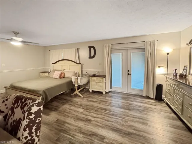 Bedroom with french doors, dark wood finished floors, access to exterior, ceiling fan, and a textured ceiling