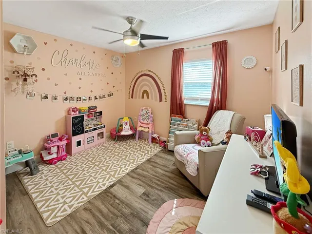 Recreation room with wood finished floors, a ceiling fan, and a textured ceiling