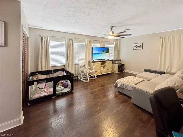 Living area featuring dark wood-style floors, a textured ceiling, and ceiling fan