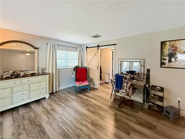 Office area with a barn door, a textured ceiling, and light wood-type flooring