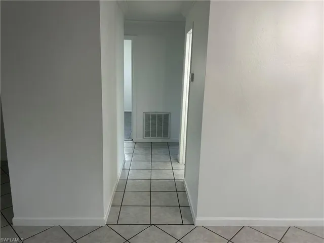 Hallway featuring ornamental molding and light tile patterned flooring