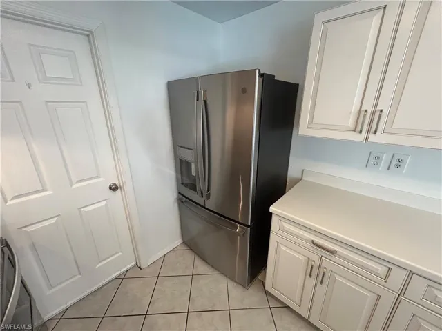 Kitchen featuring light tile patterned flooring and stainless steel fridge with ice dispenser