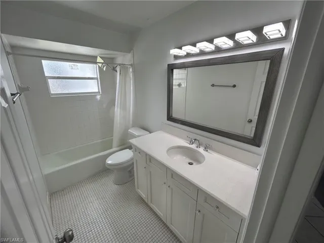 Full bathroom featuring toilet, shower / bath combo with shower curtain, vanity, and tile patterned flooring
